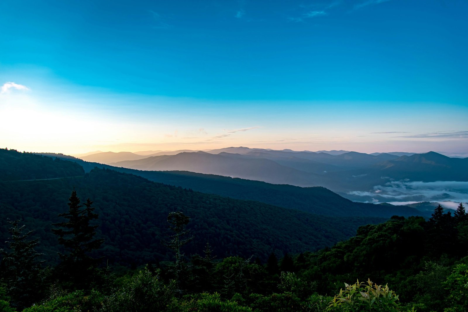 Explore a stunning mountainous vista with a blue sky and lush greenery at dawn.